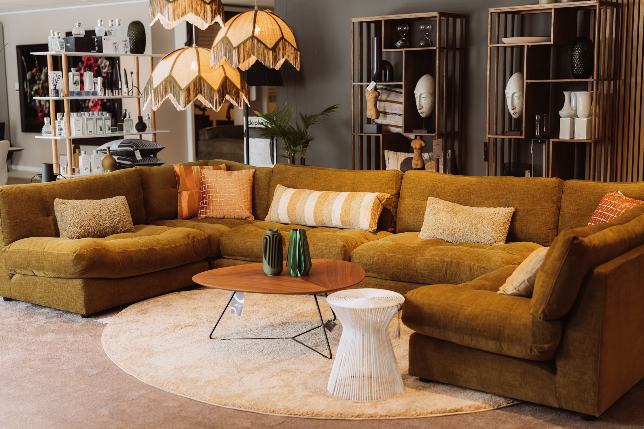 Ruime hoekbank in okergeel met kussens en een lage salontafel in de showroom van Seiger